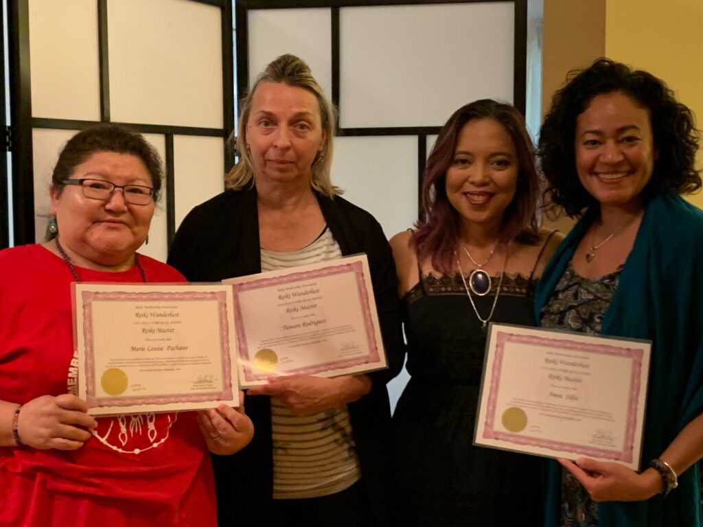 Four women holding certificates in front of a room.