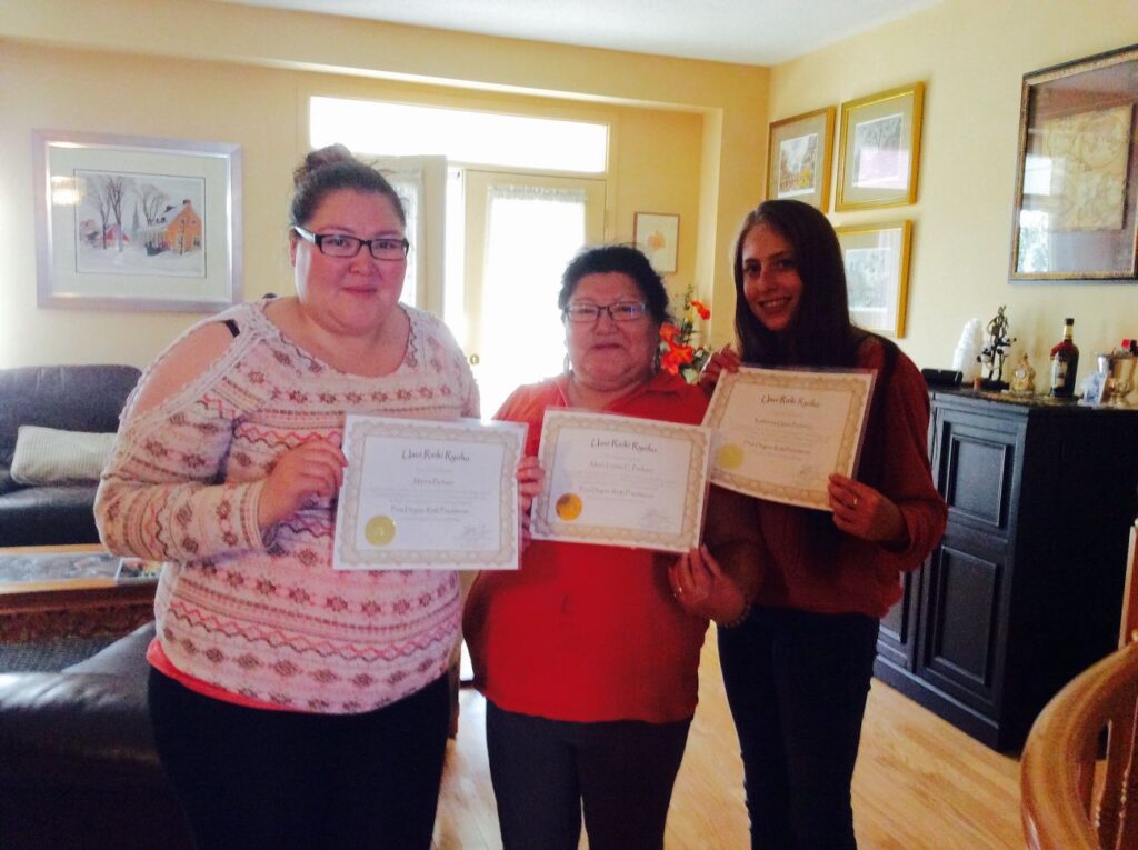 Three women holding certificates in a living room.