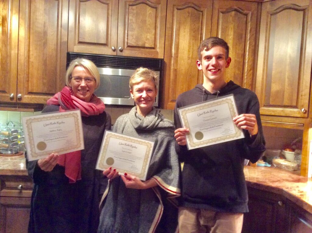 Three people holding certificates in a kitchen.