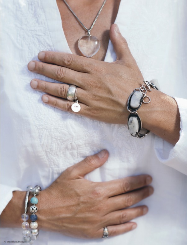 A woman wearing a white shirt and bracelets, radiating the healing energy of Holy Fire Reiki.